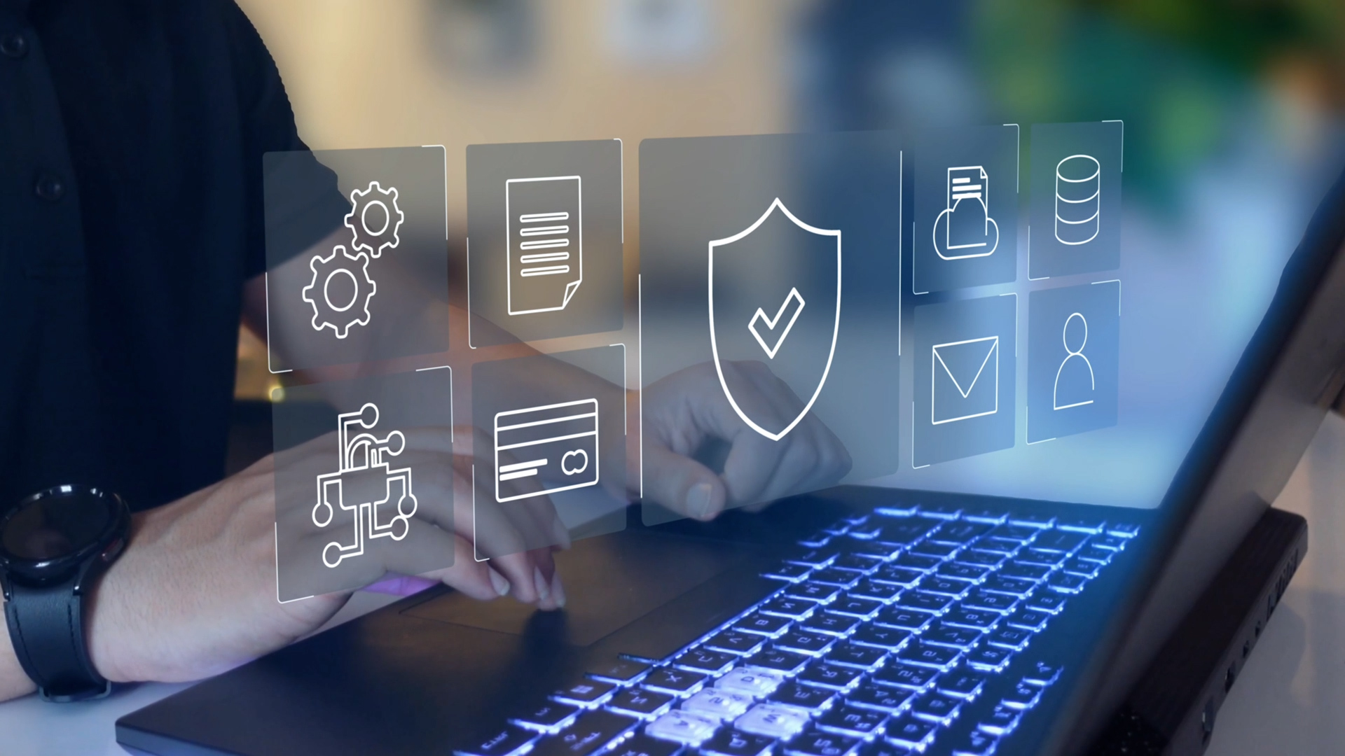 Person yn teipio ar fysellfwrdd gliniadur gyda bysellau goleuol tra bod eiconau digidol tryloyw yn ymddangos uwchben y ddyfais, gan gynnwys tarian â thic, cronfa ddata, dogfen, gerau, cerdyn credyd, sglodyn rhwydwaith, amlen neges, a phroffil defnyddiwr, yn cynrychioli seiberddiogelwch, diogelu data a systemau digidol.